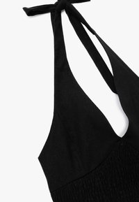 Schwarzes Neckholder-Kleid mit tiefem V-Ausschnitt, geraffter Taille und strukturiertem Stoff. Bänder am Hals ermöglichen eine Anpassung.