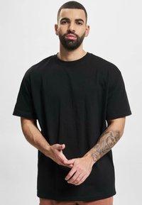 Black cotton t-shirt with short sleeves, round neckline, and relaxed fit. Features a smooth texture and no visible patterns or embellishments.