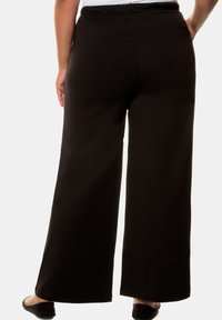 Schwarze weit geschnittene Hose mit glatter Textur, ausgestattet mit einem elastischen Bund und einer lockeren Passform, ideal für den Freizeitlook.