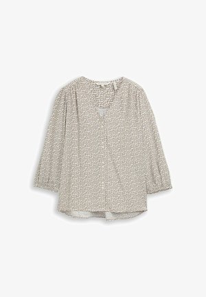 Blouse beige à manches longues avec motif géométrique noir subtil, manches légèrement froncées et encolure en V avec un petit pli à l'avant.