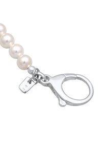 Pärlhalsband med släta krämfärgade pärlor, en silvrig hummerspärr och en liten tagg märkt '925' för sterlingsilver.