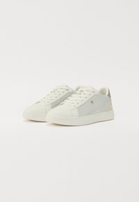 Sneaker in grigio chiaro e bianco sporco, con una texture liscia. Punta rotonda, suola piatta bianca e un branding sottile sul pannello laterale.