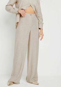 Beige linnen wijde-pijpen broek met een soepele textuur, met voorplooien en een subtiele naaddetail, gecombineerd met een bijpassende top met knopen.