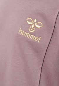 Jasnofioletowa bawełna z teksturowanym wykończeniem, z wyszytym złotym logo "hummel" oraz wzorem pszczoły.