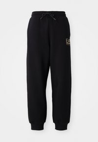 Zwarte joggingbroek met een trekkoord in de taille, elastische boorden en een klein gouden logo aan de linkerkant. Zachte stof met een gladde textuur.