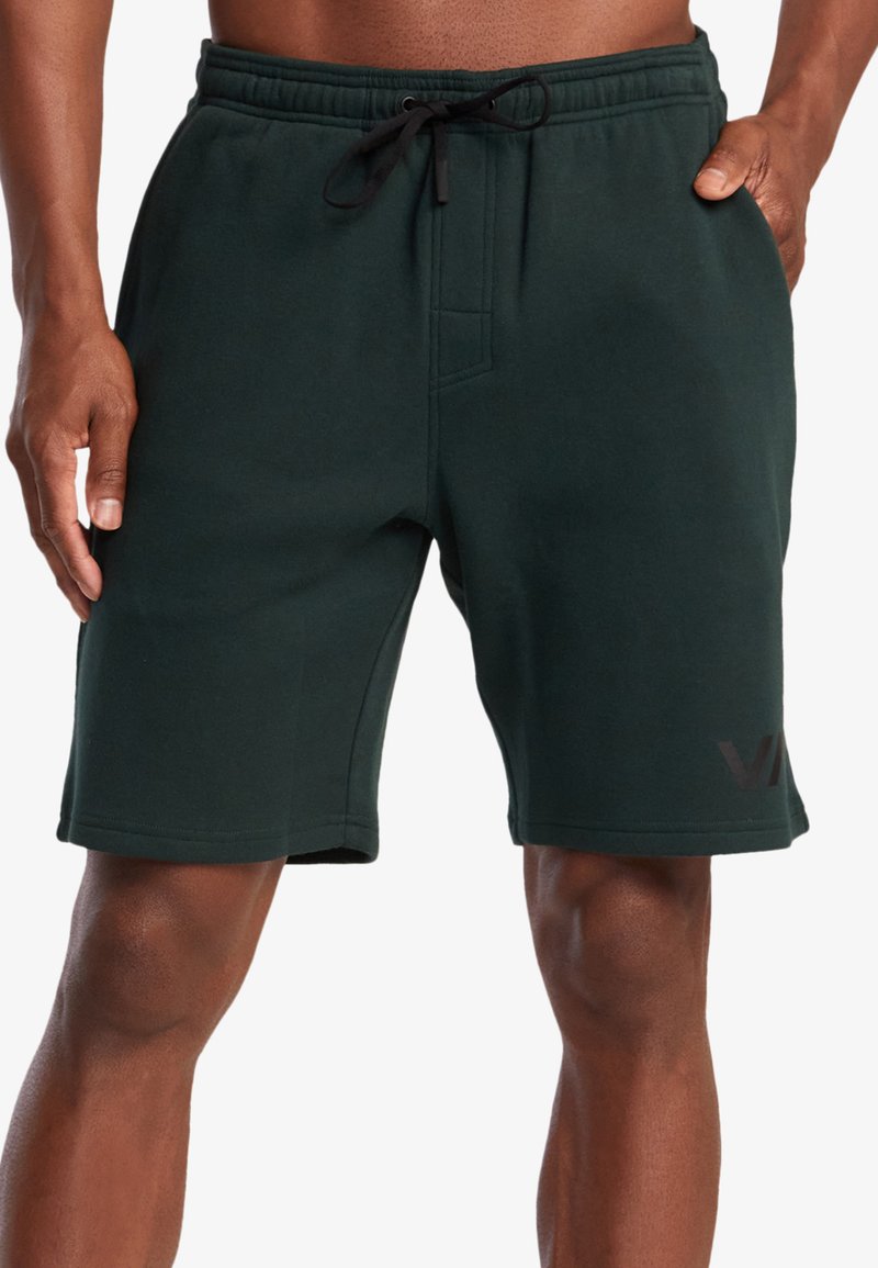 Shorts en polaire vert foncé avec une taille élastique, un cordon de serrage, des poches latérales et un logo imprimé sur la jambe gauche inférieure.