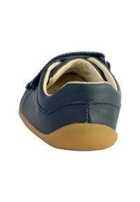 Chaussure en cuir bleu marine à enfiler, avec une forme arrondie, une doublure intérieure douce et une semelle souple en caoutchouc. Dotée d'une petite bride décorative.