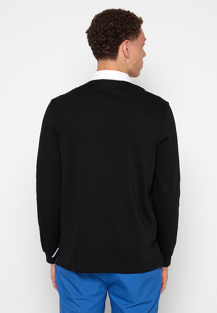Pull noir à manches longues avec texture côtelée, col rond et col blanc contrastant. Vue arrière. Design simple et classique.