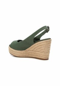 Sandalia cuña de lona verde con punta descubierta, tira trasera y suela de yute trenzado. Superficie texturizada en un tacón de cuña contorneado.