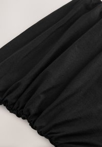 Black gathered fabric with a smooth texture, showing soft drapes and a slightly stretchy material, ideal for various garment designs.