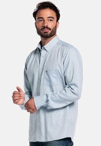 Lichtblauw, lang-jarig shirt met een button-down kraag, gestructureerde stof, een borstzak en een ontspannen pasvorm, gecombineerd met blauwe jeans.