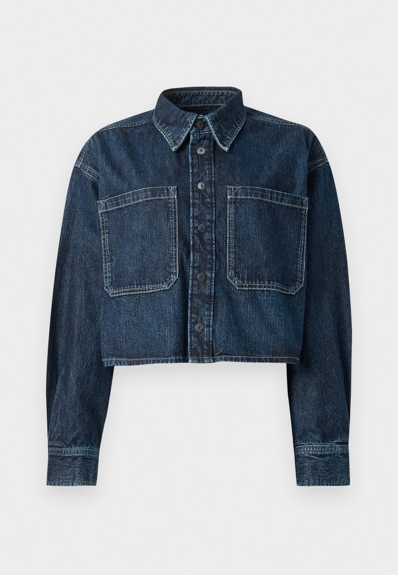 Afskåret denimjakke i mørkeblå. Har knaplukning, spidse kraver, to brystlommer og syet detaljer på ærmerne og i kanten.