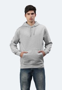 Felpa grigia realizzata in tessuto morbido, con tasca frontale, cappuccio regolabile con cordino e polsini a costine. Abbinata a jeans in denim blu.