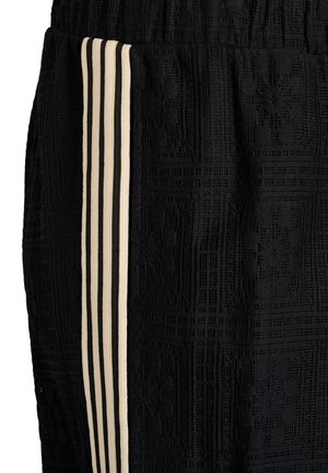 Černá tkanina s texturovaným kostkovaným vzorem, zdobená čtyřmi svislými béžovými pruhy podél bočního švu.