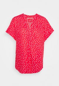 Czerwona lniana bluzka z krótkim rękawem i dekoltem w kształcie litery V, zdobiona białymi kropkami oraz dwoma kieszeniami na piersi. Lekki, przewiewny materiał.