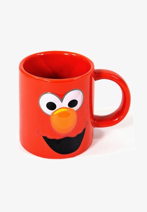 Tazza in ceramica rossa con un volto da cartone animato, occhi bianchi grandi, naso arancione e un sorriso nero. Forma arrotondata con un manico robusto.