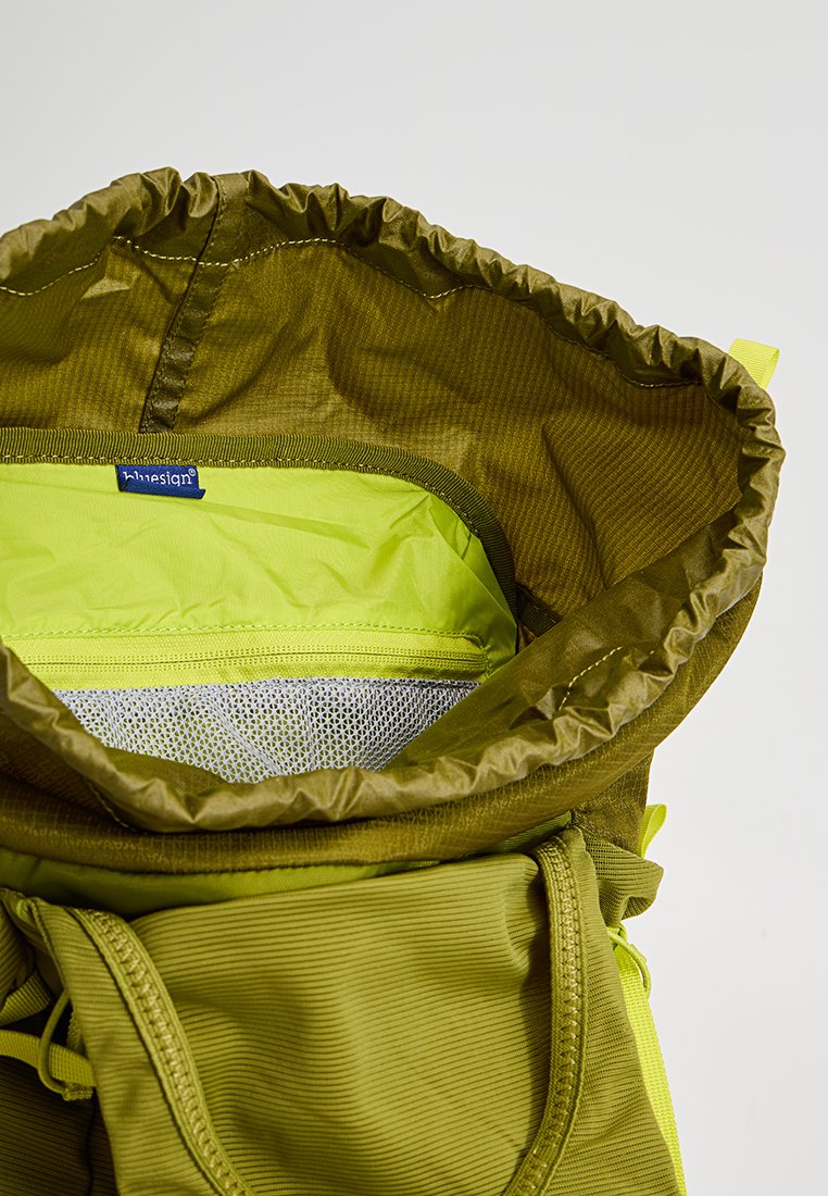 Interior de mochila impermeable verde con cierre de cordón, bolsillo de malla y forro contrastante en verde lima. Textura de tela suave y duradera.