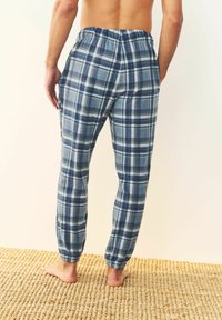 Herren Flanellpyjamahosen im blauen Karo. Elastischer Bund, schmale Bündchen, weicher Stoff. Leichtes Material, ideal für legere Freizeitkleidung.