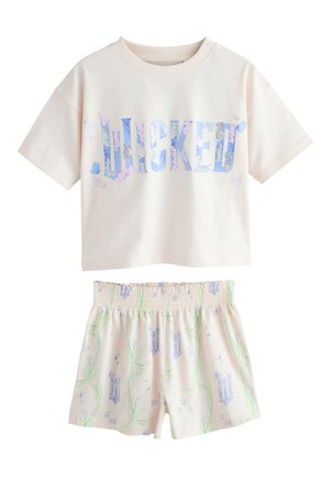 Camisa crema de manga corta con texto floral azul "WICKED" y pantalones cortos crema a juego con patrones florales verdes y azules.