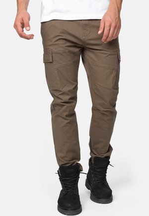 Brown cargo pants made of durable fabric with multiple side pockets, tapered fit, and paired with black lace-up boots.