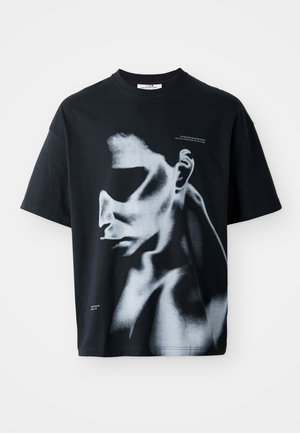 Sort bomulds T-shirt med et grafisk motiv af et ansigt i hvide og grå nuancer, med teksten "TRANSCENDENCE INTO HIGHER STATES" på brystet.