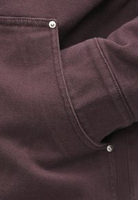 Mørk lilla jakke med en tekstureret stof, synlige sømme og sølv snap knapper på frontlommen og reverset.