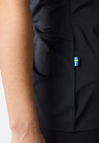 Zwarte sportshirt van ademende stof met subtiele perforaties. Bevat een klein Zweeds vlaggentag aan de zijnaad.
