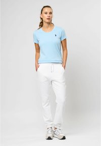 Lyseblåt bomulds t-shirt med korte ærmer, parret med hvide sweatpants med elastisk talje og manchetter, båret med sportssko.