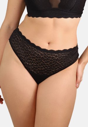 Woman wearing black lace high-waist panties and matching lace bralette, showing midsection and upper thighs against a plain background.