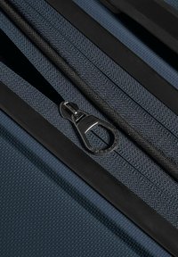 Donkerblauwe stofkoffer met rits en een zilverkleurig metalen trekker, met een gestructureerd oppervlak en duurzame zwarte randafwerking.