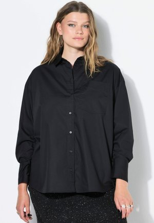 Camicia nera con bottoni, con tasca, maniche lunghe e una vestibilità rilassata. Realizzata in un tessuto morbido con una finitura opaca, presenta una ferramenta semplice.