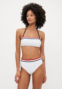 Bikini blanc avec un haut sans bretelles et un bas taille haute, ornés de rayures rouges et bleu marine le long des bords. Texture lisse.