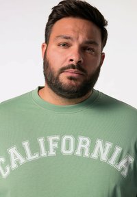Zelená mikina s potiskem "CALIFORNIA" velkými bílými písmeny. Kulatý výstřih a texturovaná tkanina, ideální pro volný čas.