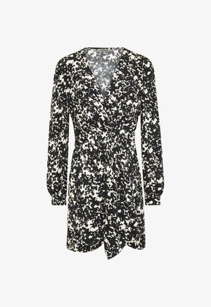 Robe imprimée en noir et blanc avec des manches longues, décolleté en V profond, taille cintrée et jupe ample et fluide, présentant un détail à nouer sur le devant.