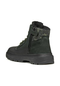 Botas de ante verde con una suela de goma negra texturizada, que cuentan con un panel de camuflaje, cierre de cremallera y un lazo para ponerlas fácilmente.