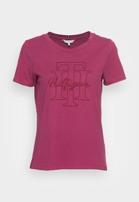 T-shirt rosa a maniche corte in cotone, con un grande logo grafico "Hilfiger" in rosa scuro al centro e colletto girocollo classico.