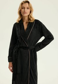 Czarny szlafrok z weluru z kołnierzem szalowym, różowymi lamówkami i paskiem do zawiązania. Długie rękawy oraz miękka, gładka faktura.