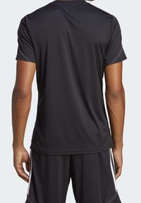 Svart herrsportt-shirt med kort ärm, tillverkad av fukttransporterande tyg, har vita sidostråk och en avslappnad passform.