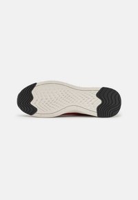 Sole of a sneaker with white textured center and black rubber grips on heel and toe, displayed against a white background.