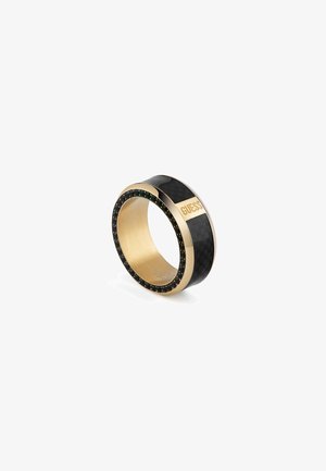 Gold-tone ring featuring a black carbon band, adorned with small black stones and engraved with the brand name "GUESS" on the side.