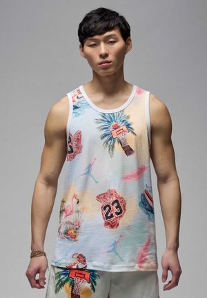 Jonge man in een kleurrijk mouwloos shirt met patronen van basketbal, palmbomen, flamingo's en rugnummer 23 op een lichte achtergrond.