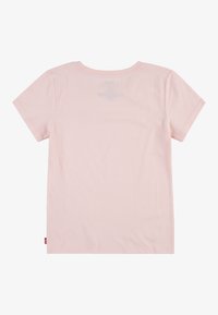 Camiseta de manga corta color rosa claro, con cuello redondo, fabricada en suave algodón, dobladillo plano y una pequeña etiqueta de marca roja en el lado izquierdo.