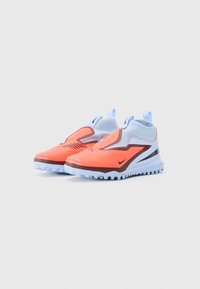 Jasne oranžové a svetlomodré športové tenisky na obutie s textúrovanými podrážkami, pútkami a čiernymi logami Nike swoosh.