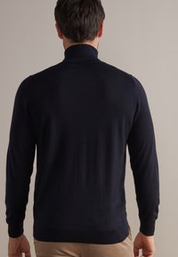 Maglione blu navy a collo alto, con maniche lunghe e polsini a coste. Tessuto morbido con design aderente. Stile minimalista.