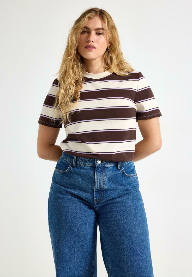 T-shirt a maniche corte a righe nei colori crema, marrone e viola con scollo rotondo, abbinato a jeans in denim blu a vita alta.