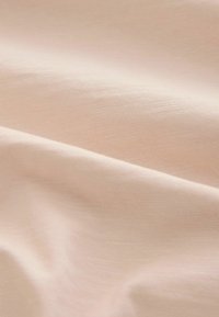 Soft, light beige fabric with gentle folds and a smooth, fine knit texture.