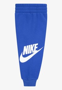 Pantaloni de trening albaștri realizați din material moale. Talie elastică cu detaliu striat. Logo mare alb Nike pe piciorul stâng. Manșete conice la glezne.
