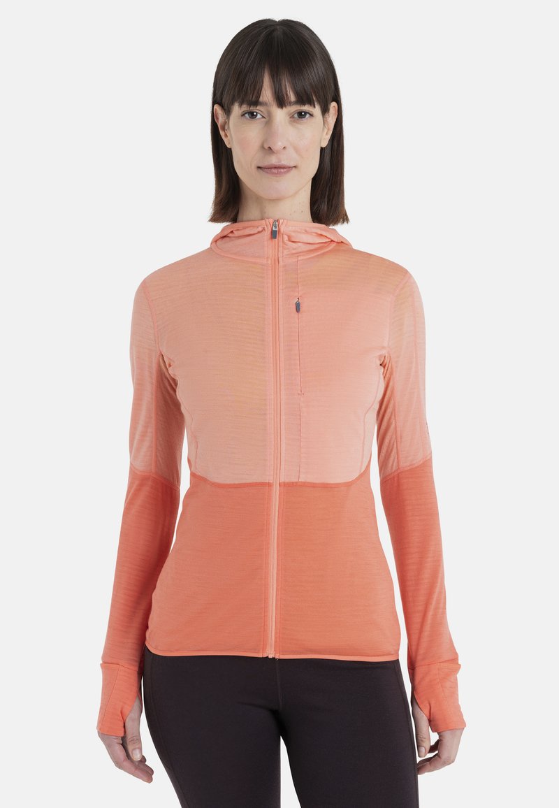 Veste à capuche zippée dans des nuances de corail, dotée de manches longues, d'une finition texturée et d'ouvertures pour les pouces aux poignets. Idéale pour les vêtements de sport.