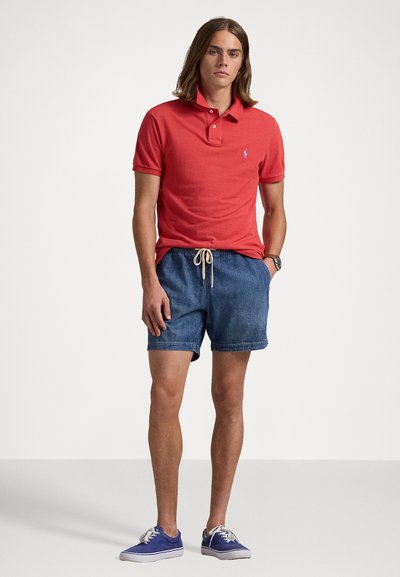 Röd bomullspolo, denimshorts med snörning och blå sneakers. Avslappnad passform, korta ärmar och logotypdetalj på skjortan.