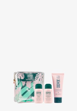 El conjunto de cuidado del cabello de Coco & Eve incluye un estuche transparente con un diseño de hojas tropicales en verde y rosa, dos botellas rosas y un tubo rosa.